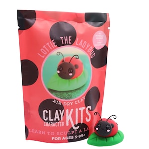 May include: A red package with black polka dots features a clay kit for sculpting a ladybug. The kit includes all materials and instructions. A finished ladybug model sits on a green leaf, next to the package. The text on the package says "Lottie the Ladybug".