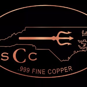 May include: A copper-colored logo on a black background. The logo features the outline of North Carolina with a trident and the letters "sCc". Below the logo, the text reads ".999 FINE COPPER". The logo is enclosed in an oval.