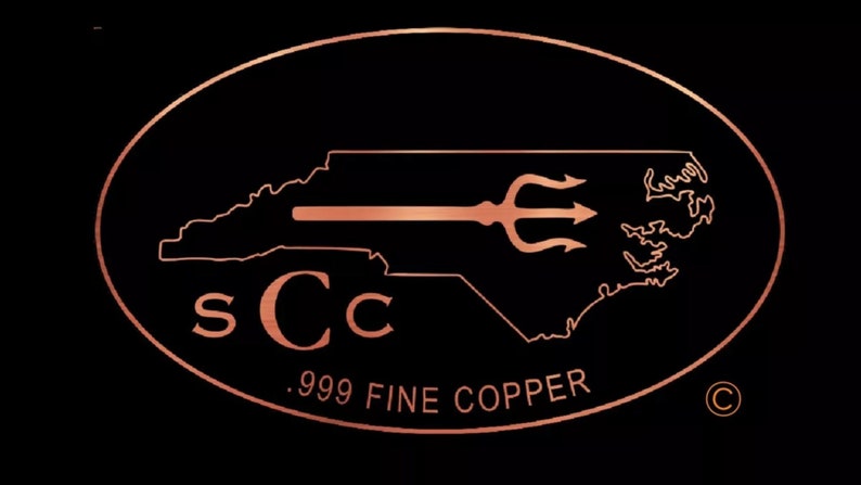 May include: A copper-colored logo on a black background. The logo features the outline of North Carolina with a trident and the letters "sCc". Below the logo, the text reads ".999 FINE COPPER". The logo is enclosed in an oval.