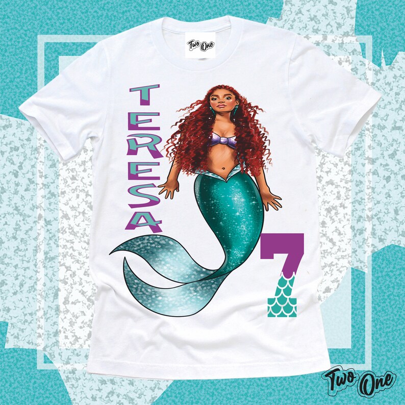 May include: White t-shirt with a mermaid illustration, the name "TERESA" in purple text, and the number "7" in purple with a teal scale pattern. The mermaid has long red hair, a teal tail, and a purple seashell bra.