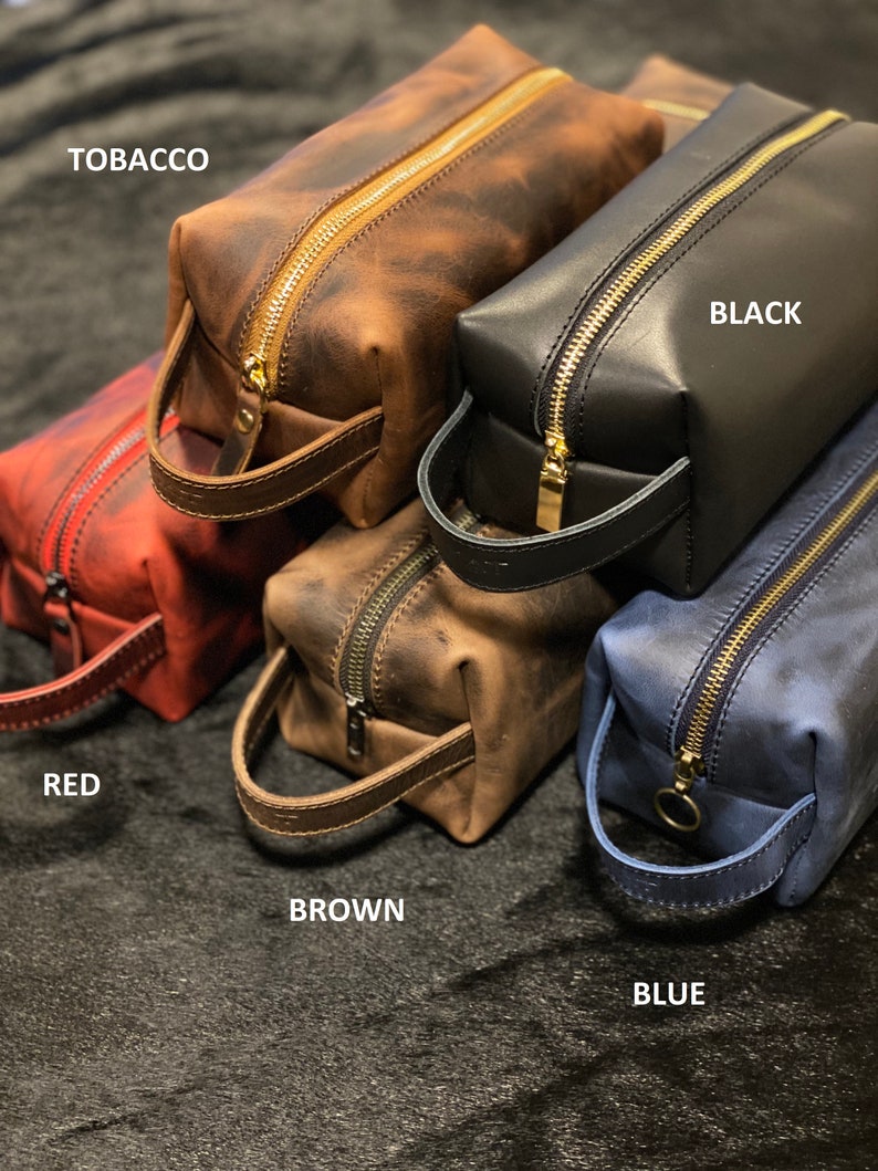 May include: Five leather zippered pouches in different colors: red, brown, tobacco, black, and blue. Each pouch has a gold zipper and a leather handle.