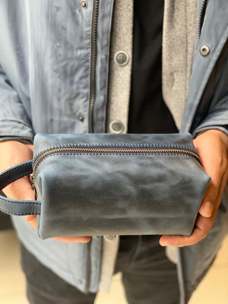 May include: A dark blue leather travel toiletry bag with a zipper closure and a leather handle.