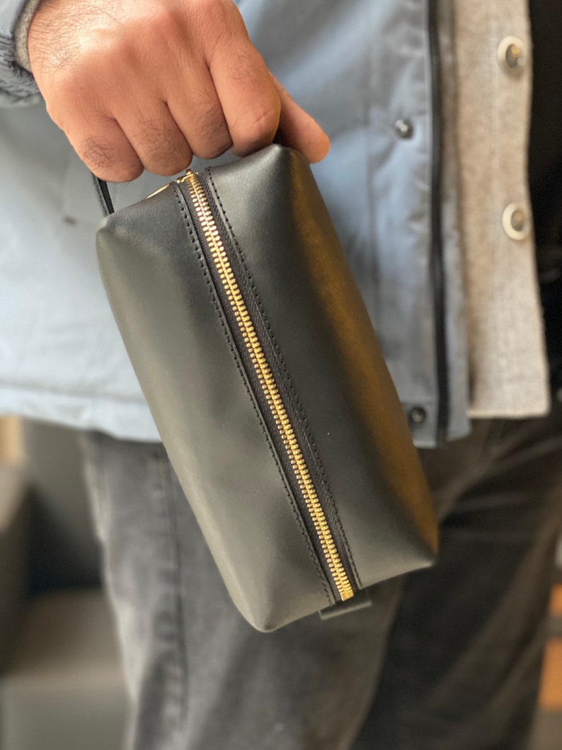 May include: A black leather zippered toiletry bag with a gold zipper.
