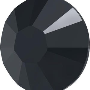 May include: A faceted, dark gray crystal with a circular shape. The crystal has multiple flat surfaces that reflect light, creating a sparkling effect. The crystal's center is a darker shade of gray.