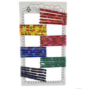 Puede incluir: Un juego de seis pinzas para el pelo de colores con motivos florales. Las pinzas están dispuestas en filas en una tarjeta blanca con el texto "High Fashion" impreso en ella.