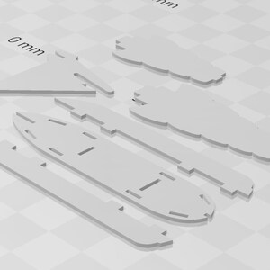 May include: A set of five white paper model boat pieces. The pieces are cut out and ready to be assembled. The pieces are labelled with measurements in millimetres.