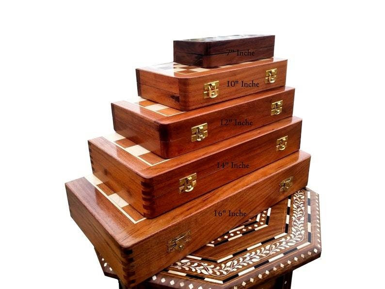 Op de afbeelding: Een stapel houten schaak- en speldozen in verschillende maten, vari&euml;rend van 18 cm tot 41 cm. De dozen zijn diep bruin van kleur met goudkleurige sluitingen. De schaakborden hebben een licht en donker vierkant patroon.