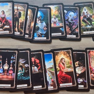 Könnte beinhalten: Ein Set Tarotkarten mit schwarzen Rahmen und goldenen Akzenten. Die Karten zeigen farbenfrohe Illustrationen von Menschen, Tieren und Objekten. Die Karten sind in zwei Reihen angeordnet, wobei die obere Reihe die Karten "Drei der Notizbücher", "Page of Swords", "XVIII - Der Mond", "Ass der Tintenfässer", "XIII - Tod", "Neun der Tintenfässer" und "Zwei der Tintenfässer" zeigt. Die untere Reihe zeigt die Karten "Drei der Tintenfässer", "Neun der Federn", "Der Teufel", "VIII - Stärke", "Königin der Diamanten", "Sieben der Federn" und "Zehn der Tintenfässer".