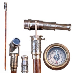 May include: A collection of nautical-themed items, including a wooden walking stick, a brass telescope with the text "MARINE TELESCOPE WAVE NAUTICAL", and a compass. The telescope is mounted on a decorative brass base.