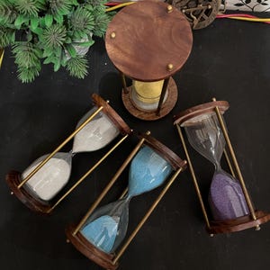 以下が含まれることがあります： 木製のフレームと真鍮のサポートが付いた砂時計のコレクション。内部の砂は白、青、紫です。黄色の砂が入った大きな砂時計も存在します。装飾的な時計。