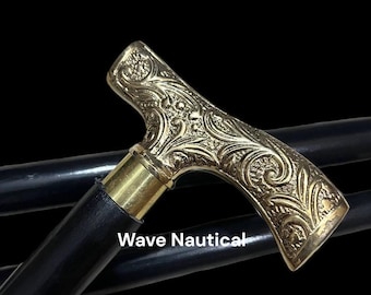 Op de afbeelding: Een zwarte houten wandelstok met een messing handvat met een ingewikkeld bloemmotief. Het handvat is T-vormig en heeft een gebogen bovenkant. De tekst "Wave Nautical" is zichtbaar op de stok.