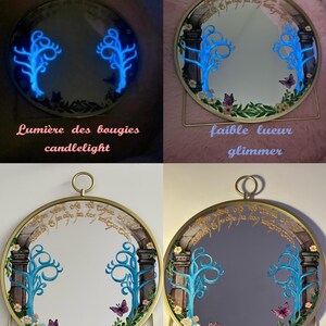 Puede incluir: Un espejo redondo con marco dorado que presenta un arco pintado, &aacute;rboles azules brillantes y mariposas. La parte superior del espejo muestra una escritura de estilo &eacute;lfico. El espejo se muestra bajo cuatro condiciones de iluminaci&oacute;n: luz de vela, tenue, luz natural y luz de l&aacute;mpara.