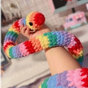 May include: A rainbow crocheted snake toy. The snake is long and has a colourful, textured design.