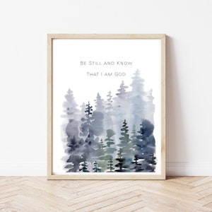 May include: A watercolor painting of a forest with the text "Be still and know that I am God". The trees are painted in shades of blue and green, and the background is a soft white.