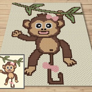 May include: A brown monkey with a pink bow hanging from a green vine. The monkey is smiling and has its arms outstretched. The background is a beige crochet fabric.