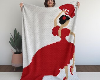 May include: A white throw blanket featuring a pixelated illustration of a flamenco dancer in a red dress, holding a red fan. The dancer's hair is black, and her shoes are red. The blanket is held up by a person.