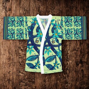 Può includere: Una vestaglia in stile kimono con base verde chiaro e un motivo ripetuto di viticci blu scuro intrecciati e fiori turchese brillante. Il capo presenta un bordo bianco a tinta unita lungo l'apertura frontale e maniche larghe a righe.