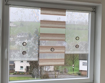 May include: A window with three roller shades. The shades have different designs: floral, striped, and solid. The window frame is white, and the shades are partially drawn, revealing a view of a green landscape and houses.
