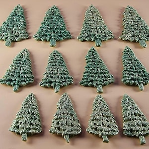 Op de afbeelding: Twaalf groene kerstboomornamenten met glitteraccenten zijn gerangschikt op een lichtbruin oppervlak. De ornamenten zijn in verschillende groentinten en hebben een textuur, ideaal voor feestelijke decoraties.