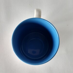 May include: A blue ceramic mug with a white handle. The mug is empty.