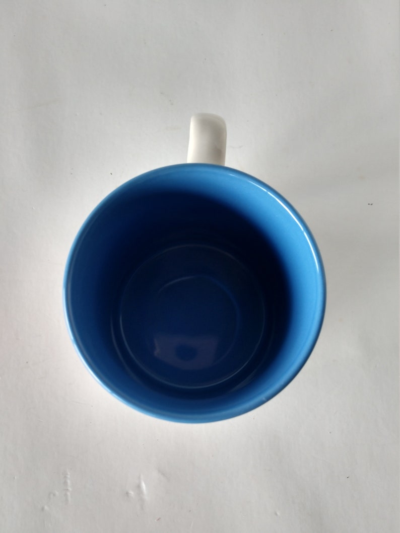 May include: A blue ceramic mug with a white handle. The mug is empty.
