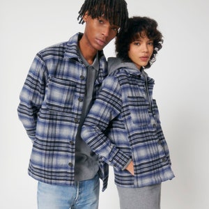 Puede incluir: Dos personas vistiendo camisas de franela a cuadros azules y blancos. Las camisas tienen un corte holgado y son abotonadas.