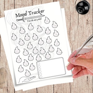 Peut inclure: Un suivi d'humeur imprimable en noir et blanc avec le titre "Mood Tracker" et le texte "You do not yield". Le suivi comprend 30 icônes de flammes numérotées et une section rectangulaire pour les notes. Une main tient une plume près du papier.