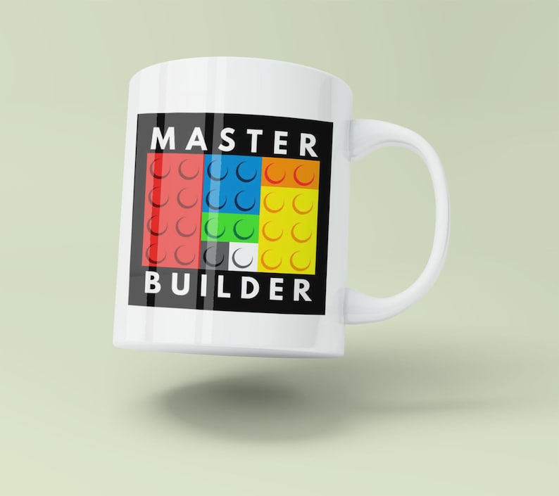 May include: White ceramic mug with a black border and the text "MASTER BUILDER" in white letters. The border contains a colorful design of interlocking Lego bricks.