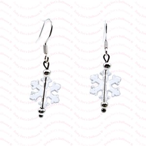Puede incluir: Un par de pendientes de plata con forma de copo de nieve. Los copos de nieve son transparentes y tienen un diseño delicado. Los pendientes son perfectos para añadir un toque de magia invernal a cualquier atuendo.