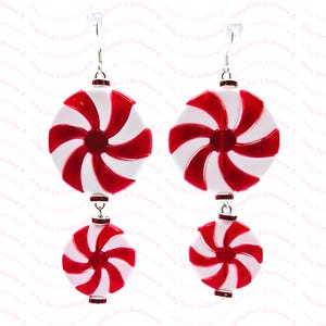 May include: A pair of dangle earrings featuring a red and white peppermint candy design. The earrings are made of metal and have a silver finish.