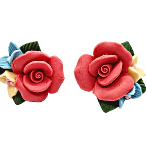 May include: A pair of red rose flower earrings with yellow, blue, and green accents. The earrings are made of polymer clay.