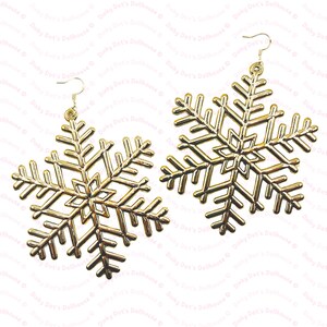 Puede incluir: Un par de pendientes de copo de nieve de oro. Los copos de nieve son detallados y tienen un diseño delicado.