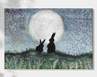 May include: A watercolor painting depicts two black rabbits silhouetted against a large, full moon. The rabbits are perched on a grassy hill, with a starry sky and floral details. The artwork has a dreamy, whimsical quality.