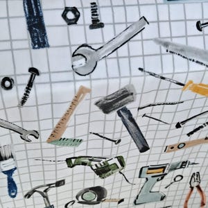 May include: White fabric with a grid pattern featuring illustrations of various tools, including wrenches, hammers, saws, and drills. The tools are in shades of gray, blue, and yellow.
