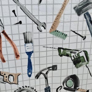 May include: White fabric with a grid pattern featuring a repeating design of various tools. The tools include a wrench, ruler, hammer, saw, drill, and pliers, in shades of gray, brown, blue, and green.