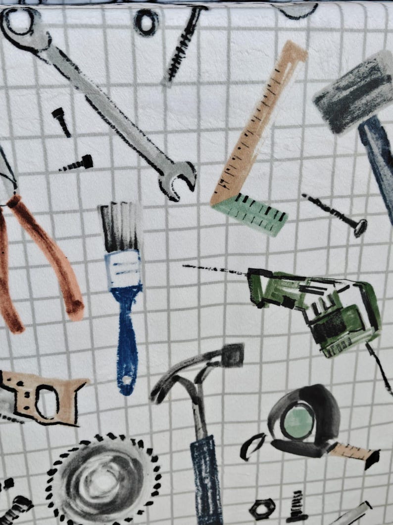 May include: White fabric with a grid pattern featuring a repeating design of various tools. The tools include a wrench, ruler, hammer, saw, drill, and pliers, in shades of gray, brown, blue, and green.