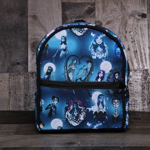 May include: A blue and black backpack with a print of characters from the movie "The Nightmare Before Christmas".