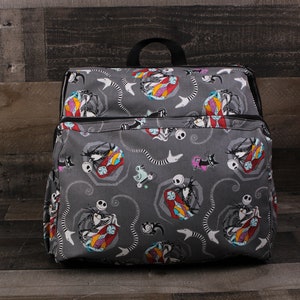 May include: A gray canvas backpack with a repeating pattern of Jack Skellington and Sally from The Nightmare Before Christmas. The backpack has a black zipper and black straps.