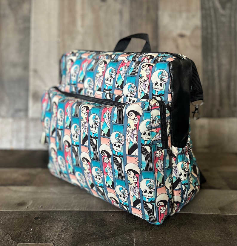 Puede incluir: Una mochila de patr&oacute;n azul y rosa con detalles negros. El patr&oacute;n presenta una imagen repetida de Jack Skellington y Sally de Pesadilla antes de Navidad.