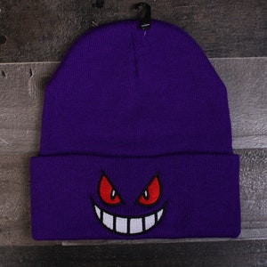 May include: Purple beanie with a white and red embroidered Gengar face.