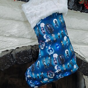 May include: A blue Christmas stocking with a white faux fur cuff. The stocking is decorated with a repeating pattern of characters from a movie. The stocking is hanging over a fireplace.