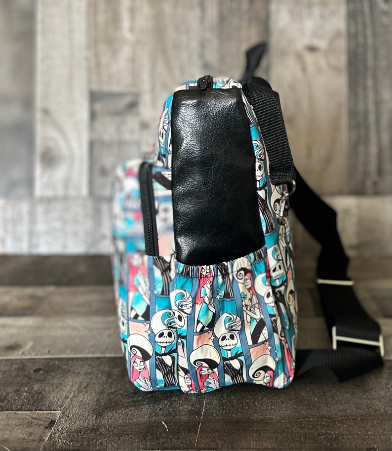 Puede incluir: Una mochila de patr&oacute;n azul y blanco con un bolsillo de cuero negro en la parte posterior. La mochila tiene una correa negra ajustable y un cierre de cremallera.