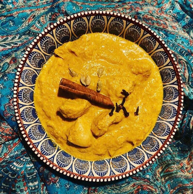 Peut inclure: Un bol de curry jaune avec du poulet, des b&acirc;tonnets de cannelle et des clous de girofle. Le bol a un motif bleu et blanc.