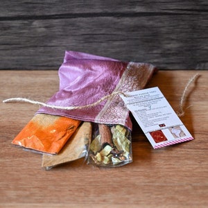 May include: A pink silk pouch tied with twine and containing three small bags of spices. The pouch is labeled "Shibori Panela Tote" and "Rooibos Blend".