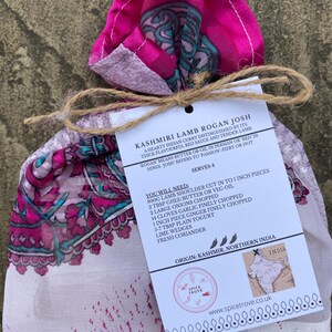 May include: A white card with the text "Kashmiri Lamb Rogan Josh" and a recipe for the dish. The card is tied with twine and wrapped in a pink and white patterned fabric.