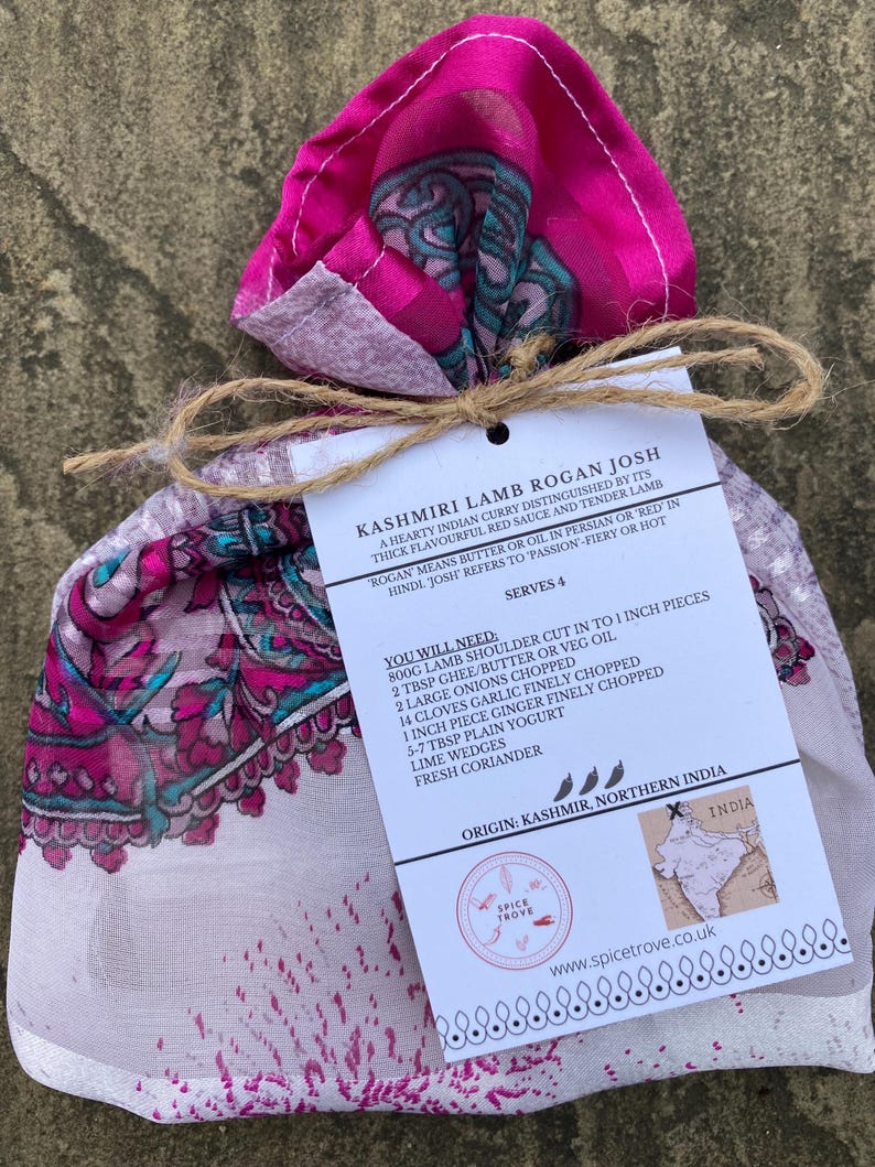 May include: A white card with the text "Kashmiri Lamb Rogan Josh" and a recipe for the dish. The card is tied with twine and wrapped in a pink and white patterned fabric.