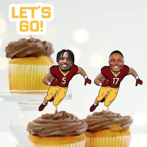 May include: Two football player cupcake toppers with the text "Let's Go!" on a brown cupcake with chocolate frosting. The football players are wearing burgundy and gold uniforms with the numbers 5 and 17.
