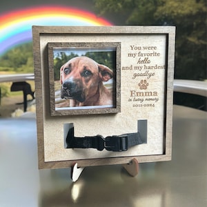 May include: A wooden photo frame with a brown background and a black collar cutout. The frame has a picture of a brown dog with a rainbow in the background. The text on the frame reads "You were my favourite hello and my hardest goodbye Emma in loving memory 2011-2024".