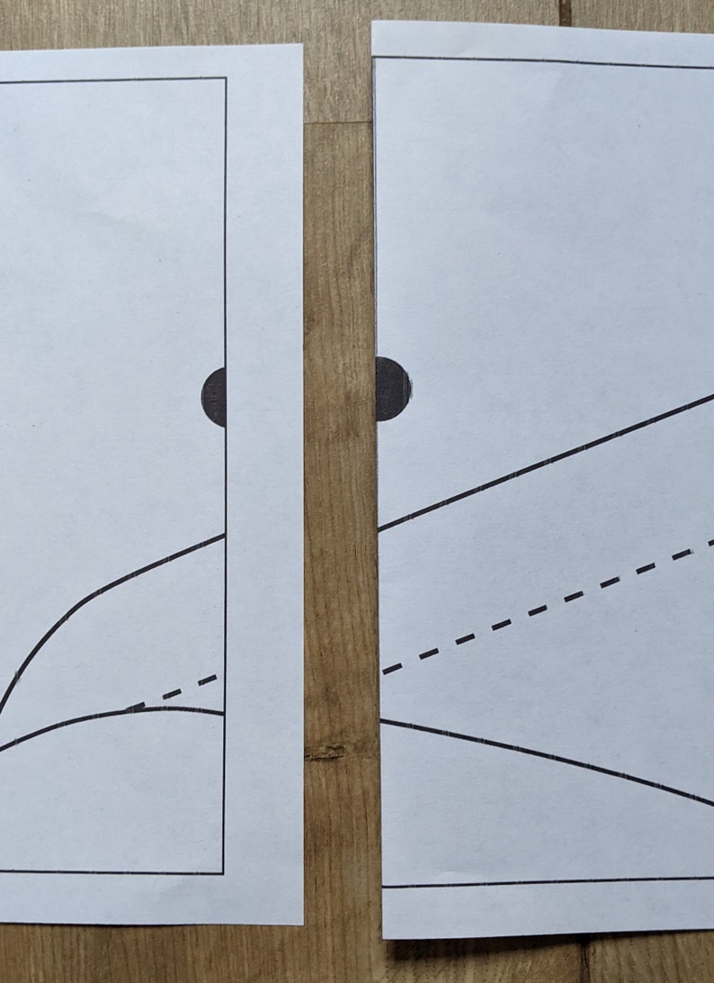 May include: Two white sheets of paper with black lines and circles drawn on them. The sheets are placed side by side on a wooden surface.