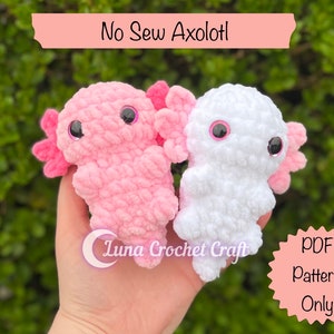 Peut inclure: Deux peluches axolotl crochetées, l'une rose et l'autre blanche, avec des yeux noirs. Les peluches sont tenues dans une main. Le texte "No Sew Axolotl" et "PDF Pattern Only" est visible sur l'image.